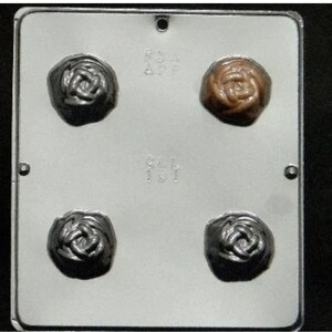 Może przedstawiać: Biała plastikowa forma z czterema wnękami w kształcie róż. Dwie wnęki są wypełnione ciemnymi czekoladowymi różami, a dwie wnęki są wypełnione jasnobrązowymi czekoladowymi różami.