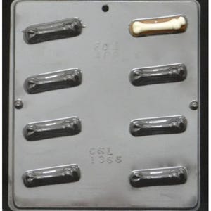 May include: A silver metal mold for making chocolate dog bones. The mold has eight cavities and the text "CWL 1965" is visible on the bottom.