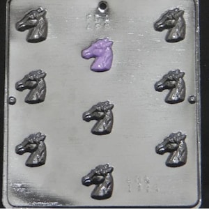 May include: A silver metal mold with eight horse head cavities. The mold is designed for making chocolate or candy. The mold has a purple horse head in one of the cavities.