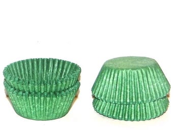 May include: Green cupcake cases, a stack of three cases and a stack of two cases.