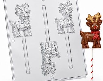 May include: A clear plastic candy mold featuring three reindeer-shaped cavities with integrated stick channels, accompanied by a finished brown chocolate reindeer lollipop with gold-dusted antlers and a red scarf on a white and red striped stick.