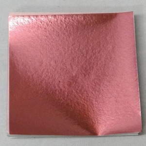 Puede incluir: Un paquete de hojas de oro rosa. Las hojas son lisas y tienen un brillo metálico.