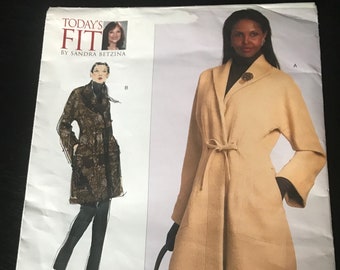 May include: Vogue Patterns V1060 sewing pattern for a long, belted coat with a shawl collar. The pattern includes instructions for two different styles, one with a more fitted silhouette and one with a looser fit. The pattern is printed on white paper with black text and illustrations.