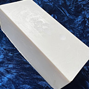 May include: A large, rectangular block of white soap. The soap is smooth and has a slightly textured surface.
