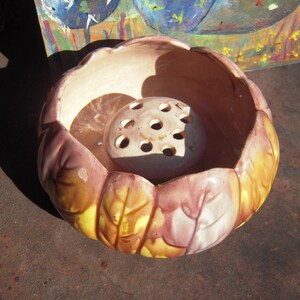 May include: A vintage ceramic flower frog and bowl set. The bowl is shaped like a flower with yellow, brown, and pink petals. The flower frog is off-white with multiple holes. The set is designed for arranging flowers.