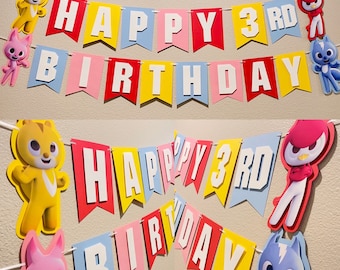 Puede incluir: Un banner colorido de Feliz 3er Cumpleaños con personajes de dibujos animados. El banner está hecho de papel y tiene una cuerda para colgar. Los personajes son una ardilla, un pájaro y un gato.