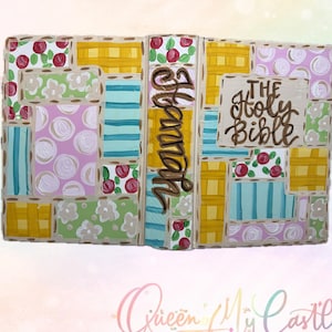 May include: Hand-painted decorative book with a patchwork design. The cover features a variety of patterns, including floral, stripes, and polka dots, in shades of pink, yellow, green, and blue. The spine reads "Hannah" and the front cover says "The Holy Bible".