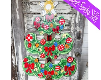 May include: A green Christmas tree door hanger with red, white and blue baubles, bows and candy canes. The tree is made of wood and has a rustic look.