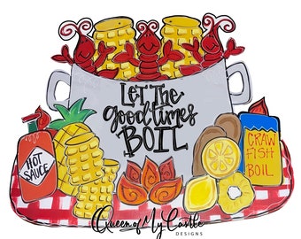 May include: A white pot with red crawfish, corn on the cob, lemons, and potatoes. The pot is on a red and white checkered tablecloth. The text "Let The Good Times Boil" is written on the pot. The text "Queen of My Castle Designs" is written below the pot.