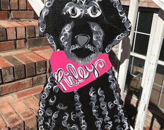 May include: Black and white painted wooden cutout of a dog with curly hair wearing a pink collar with the name "Riley" written on it.