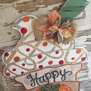 May include: A white and brown door hanger with a pumpkin design and the text "Happy Fall Y'all". The hanger is decorated with a burlap bow and orange and brown ribbon.