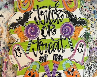 May include: A Halloween-themed wooden sign with a green and white striped background. The sign features the words "Trick or Treat" in black script, along with bats, lollipops, ghosts, and jack-o'-lanterns.