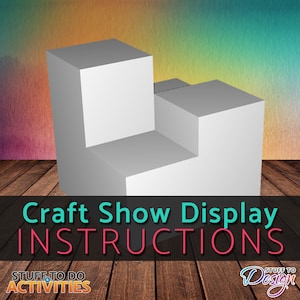 May include: Craft show display instructions. A white three-tiered display made of cardboard boxes. The display is on a wooden floor.