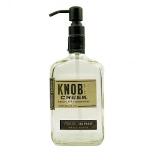 May include: A clear glass bottle with a black pump dispenser. The bottle has a rectangular shape and features a label with the text "Knob Creek Kentucky Bourbon Whiskey 100 Proof Small Batch."