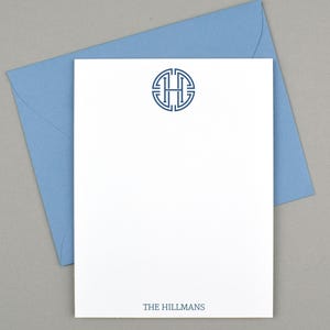 May include: White stationery with a blue monogram and matching envelope. The stationery features a circular monogram with the letter "H" and the name "THE HILLMANS" printed at the bottom in a dark blue color. The envelope is light blue.