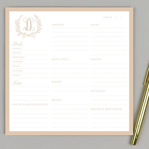May include: A printable grocery list template featuring a floral wreath with the letter "D" in the centre. The list is divided into categories such as produce, dairy, meat & deli, snacks, bakery, beverages, frozen, pantry & miscellaneous, and health & household.