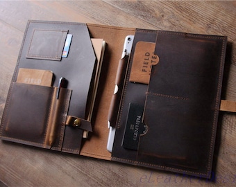 May include: A brown leather portfolio with multiple pockets and a strap. The portfolio has a pen holder, a card slot, and a pocket for a notebook. The portfolio is open to reveal a passport and a tablet.