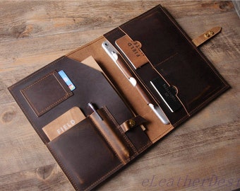 Peut inclure: Un porte-documents en cuir marron foncé doté de multiples poches intérieures, d'un passant pour stylo et d'une fermeture à pression. L'intérieur contient un carnet marqué FIELD, une fente pour carte et une poche marquée PASSAPORTO.
