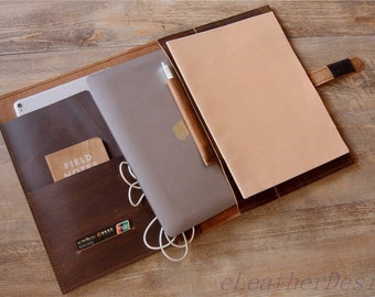 Peut inclure: Un porte-documents en cuir marron foncé doté de plusieurs poches intérieures, un ordinateur portable argenté, un stylet blanc, un carnet beige, un petit livret Field Notes et des câbles de charge blancs. L'étui comprend une fermeture à sangle.