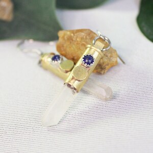 May include: A pair of earrings made from brass casings with a clear quartz crystal and a blue gemstone accent.
