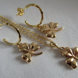 Op de afbeelding: Gouden ketting en oorbellen set met een klavertje vier hanger en bijpassende oorbellen.