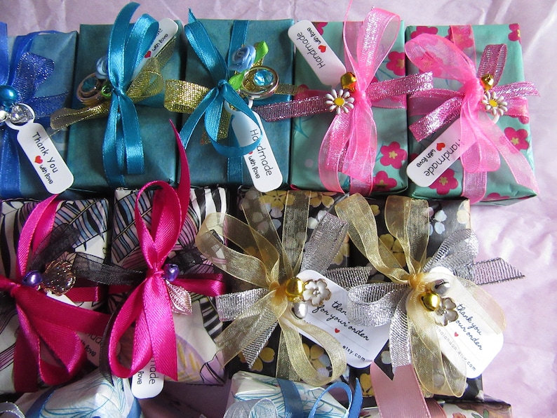 May include: Assortment of small gift boxes wrapped in various patterned papers and tied with colorful ribbons. The boxes have tags attached with the text "Handmade with love" and "Thank you".