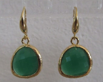 May include: A pair of gold dangle earrings with green gemstone drops. The earrings have a simple design and are perfect for everyday wear.
