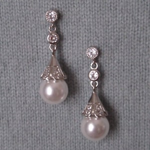 May include: A pair of silver dangle earrings with a pearlescent drop and clear crystal accents.