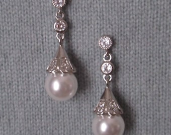 May include: A pair of silver dangle earrings with a pearlescent drop and clear crystal accents.