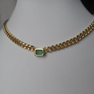 May include: A gold chain necklace with a single green rectangular gemstone pendant.
