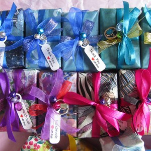 May include: Assortment of small gift boxes wrapped in various colorful patterned papers and tied with ribbons. The boxes have tags that say "Handmade with love" and "Thank you with love".