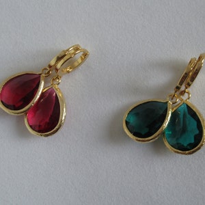 May include: A pair of gold earrings with teardrop-shaped red and green crystals.