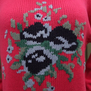 May include: A red knitted sweater with a colorful geometric design. The design features a black, green, and gray pattern.