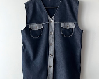 May include: A sleeveless denim vest with a button-up front and two flap pockets. The vest is a dark blue color with a light gray trim.