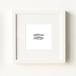 May include: A white framed print of a simple line drawing of two fish on a white background.