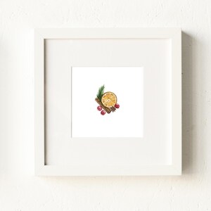 May include: A framed watercolor print featuring a slice of dried orange, a cinnamon stick, cranberries, a star anise, and a sprig of evergreen. The artwork is set against a white background within a white frame, evoking a festive, seasonal theme.