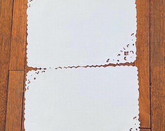 May include: Two white embroidered placemats with scalloped edges and intricate floral designs.
