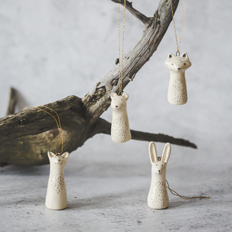 Christmas tree wild animals decoration set of four. Fox, bear, raccoon, hare ceramic ornaments hanging from a gold string.