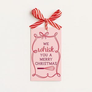 May include: A pink gift tag with the text "We Whisk You a Merry Christmas" in red script. The tag is adorned with a red whisk illustration and a red and white striped bow.