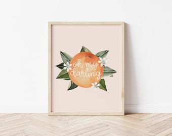 Puede incluir: Impresión en acuarela enmarcada con una naranja y la frase "oh my darling" en blanco. La naranja está rodeada de hojas verdes y flores blancas, sobre un fondo melocotón claro.