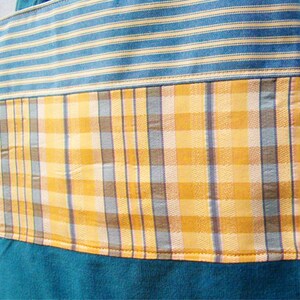 May include: A blue and yellow striped fabric tote bag with a plaid pattern in the middle. The bag is made of a soft, durable fabric and has a large capacity.