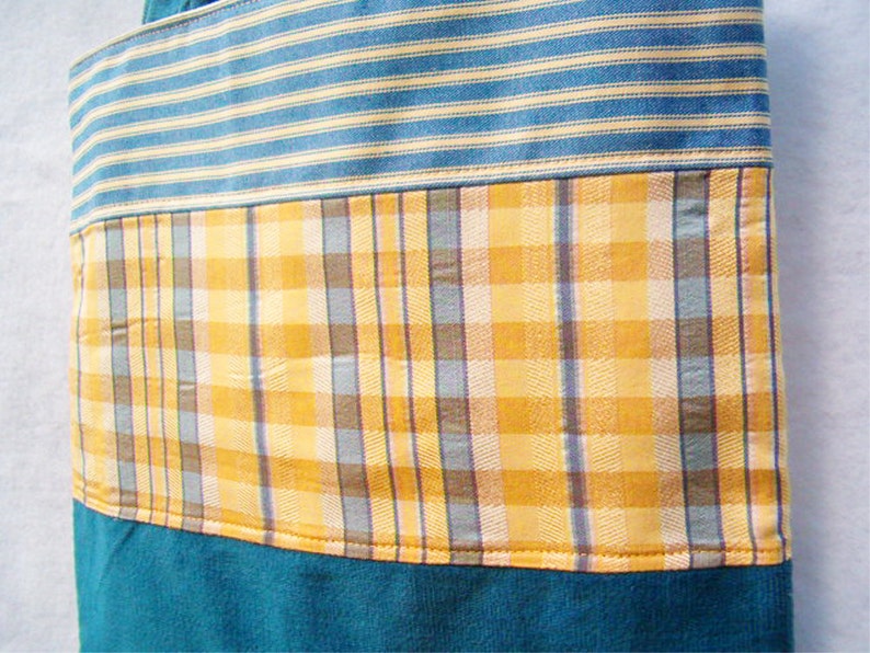May include: A blue and yellow striped fabric tote bag with a plaid pattern in the middle. The bag is made of a soft, durable fabric and has a large capacity.