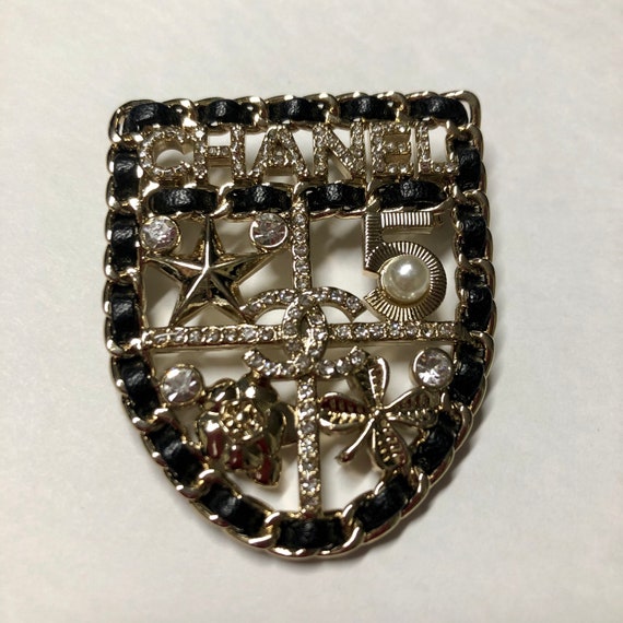 CHANEL shield brooch | black leather white rhinest