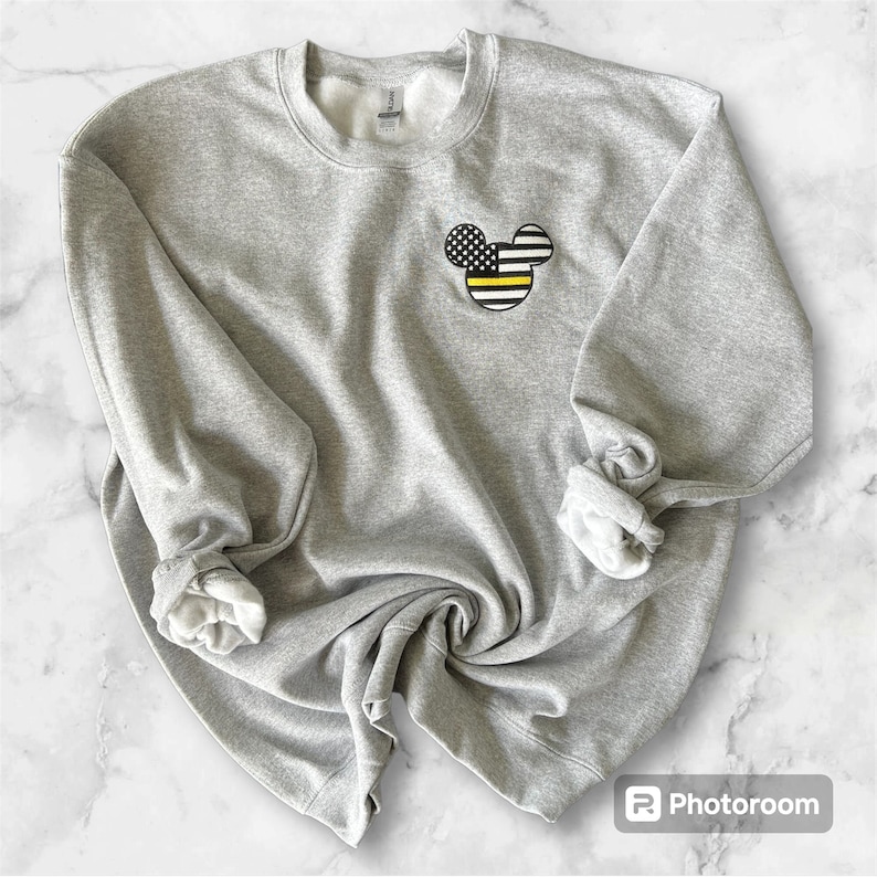 May include: Gray sweatshirt with a black and yellow American flag Mickey Mouse design on the front.