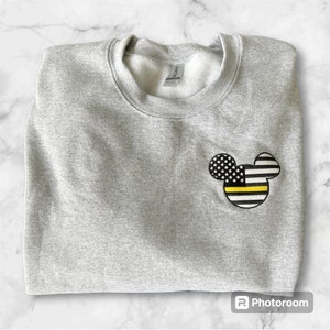 May include: Gray sweatshirt with a black and yellow American flag Mickey Mouse design on the left chest.