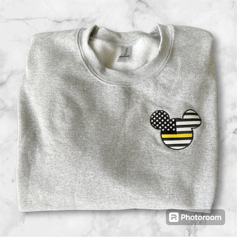 May include: Gray sweatshirt with a black and yellow American flag Mickey Mouse design on the left chest.