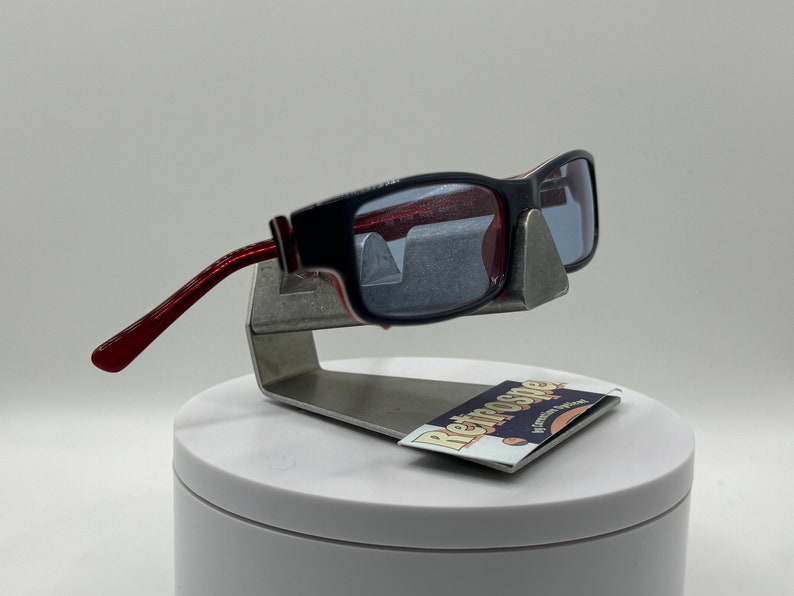 May include: Red and black sunglasses with a silver stand and a card that says "Retrospecs" with a retro-style font.