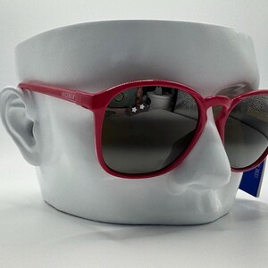 May include: A pair of pink sunglasses with dark lenses. The sunglasses are on a white mannequin head.