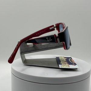 May include: Red and blue sunglasses with silver accents. The sunglasses are on a display stand with a business card that says "Retrospecs" on it.
