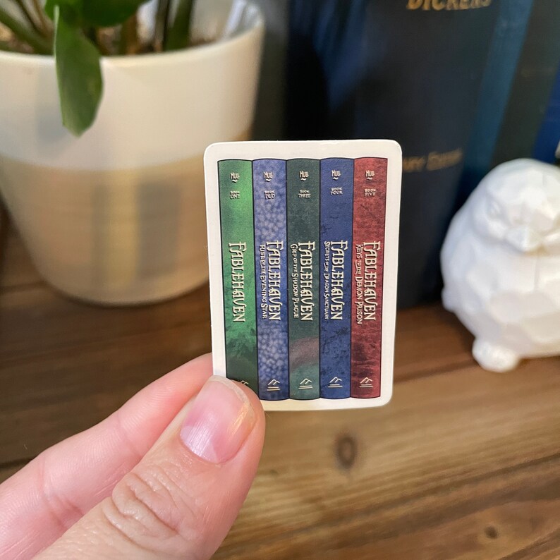 May include: A set of five paperback books with blue, green, and red covers. The books are titled "Fablehaven" and each book has a different subtitle. The books are arranged in order from left to right, with the first book being "Fablehaven: Keys to Demon Prison" and the last book being "Fablehaven:  Tufts Evening Star."